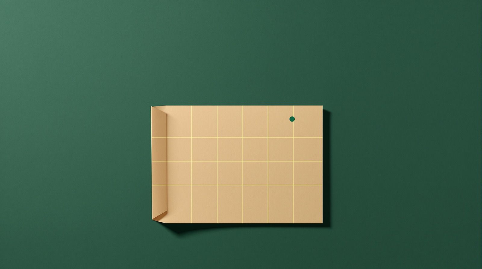 A sand colored sheet with one corner folded and thin gold grid lines, with a dusty teal circle marked on it